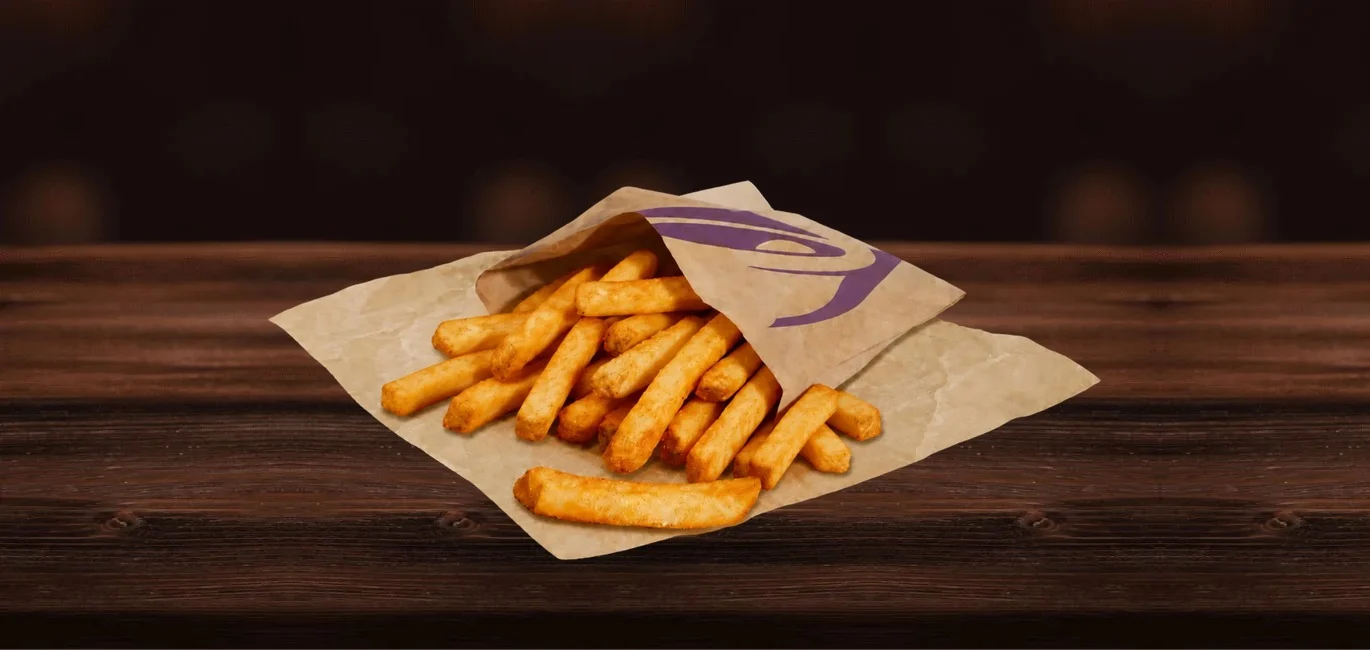 Pile of French fries spilling from a brown paper bag onto a dark wooden table.