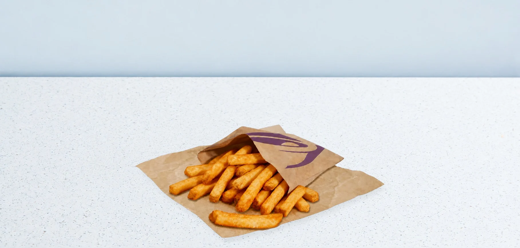 3412-xl-fries | Taco Bell Hrvatska Pile of French fries spilling from an opened brown paper bag with a purple logo on a light speckled countertop.