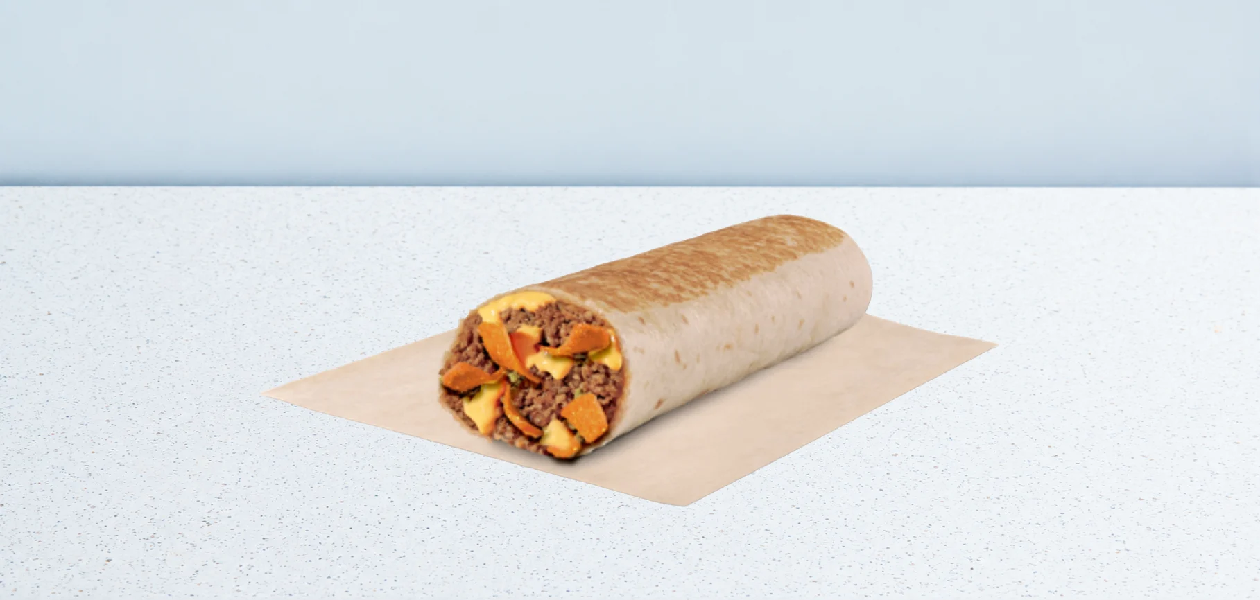 Beefy Nacho Burrito | Taco Bell Hrvatska Beef and cheese burrito with peppers on parchment paper over a speckled white countertop, with the end slightly open to show filling.